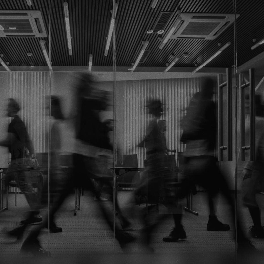 Silhouettes of people rushing through an office building.